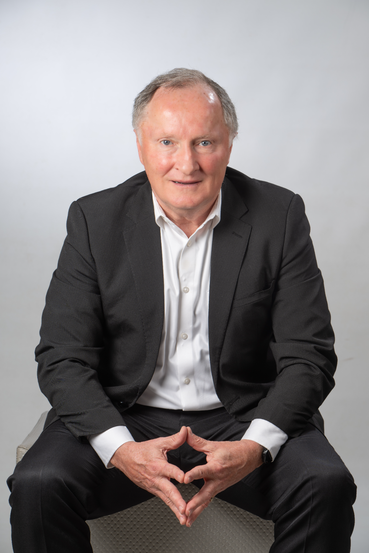 Coach Riaan van Deventer, seated, in a dark pinstripe suit and white shirt
